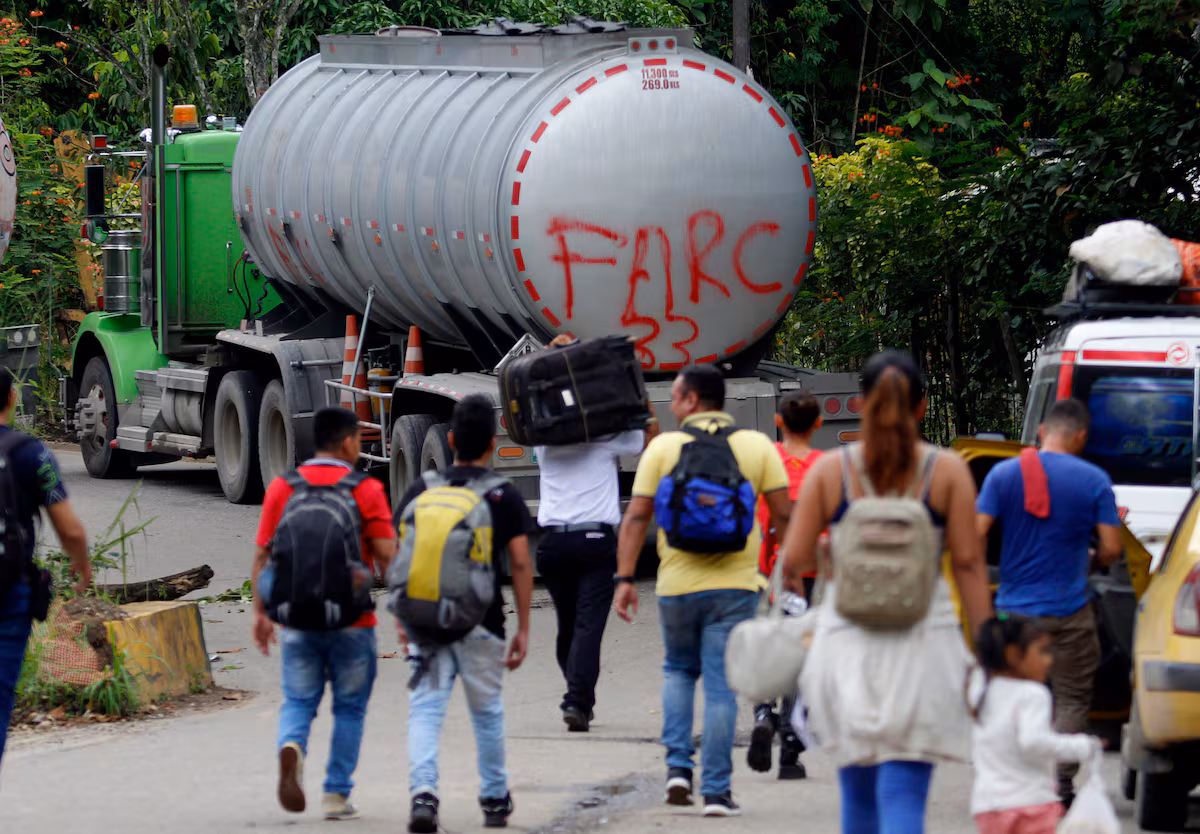 Varias personas caminan por una carretera del Catatumbo junto a un camión con la frase 'FARC 33', el 16 de agosto de 2023. Foto: Efe